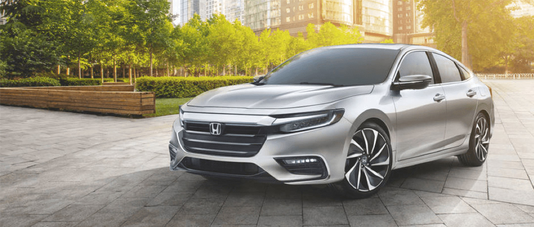 A silver Honda Insight parked in a cityscape.
