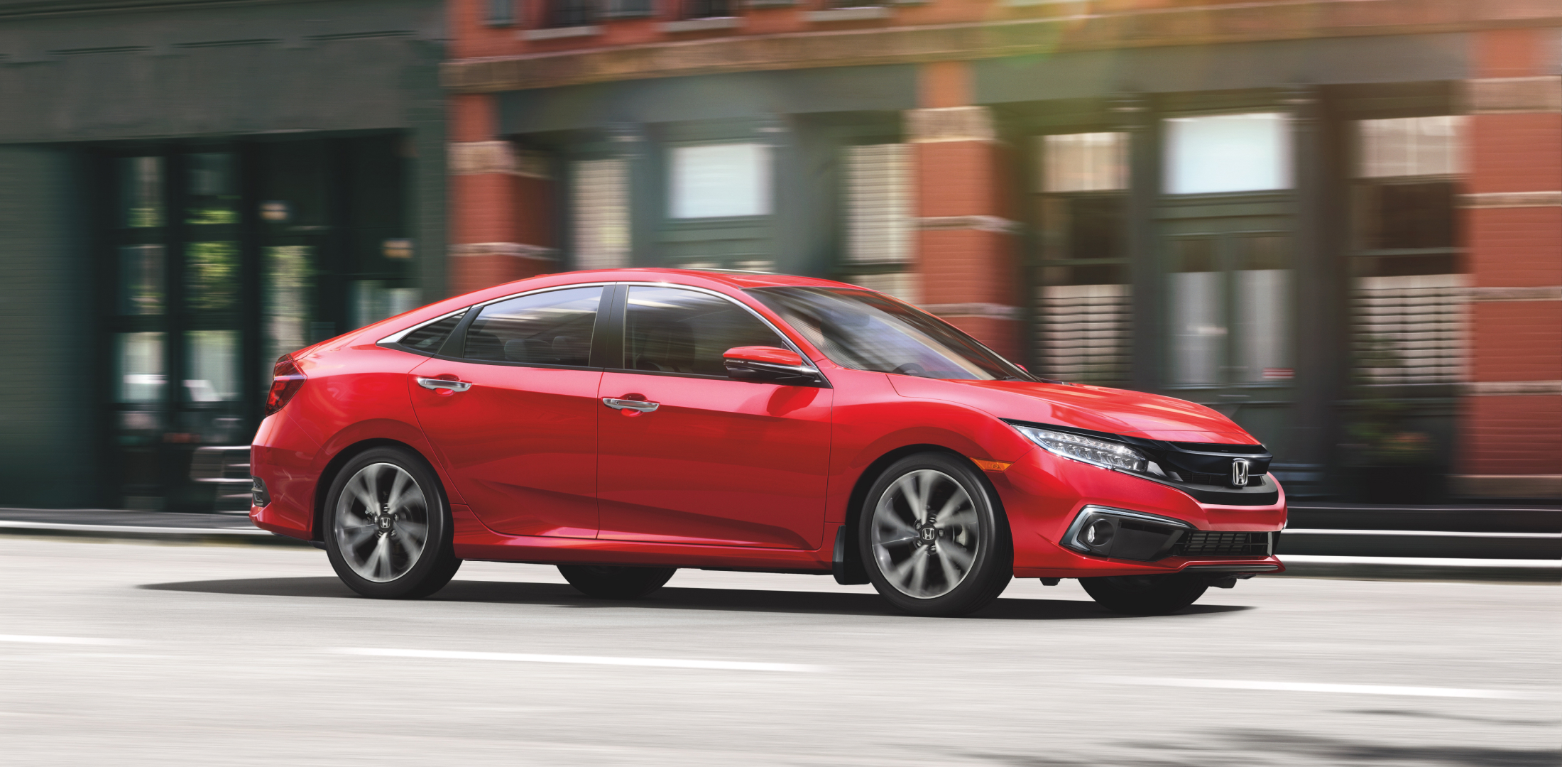Une Civic Honda rouge roule en ville.